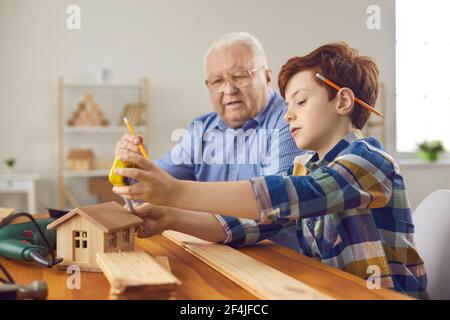 Nonno e suo nipote che fanno piccole case di legno nel loro officina di falegnameria Foto Stock