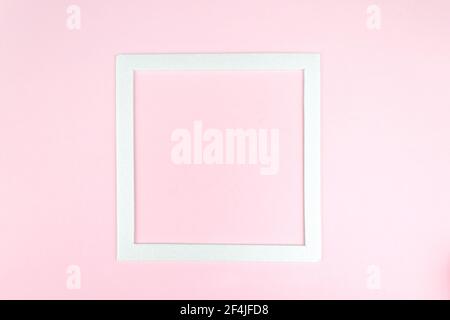 Vista dall'alto della cornice quadrata bianca su un concetto di rosa e minimalista. Mockup di schede vuote quadrate Foto Stock