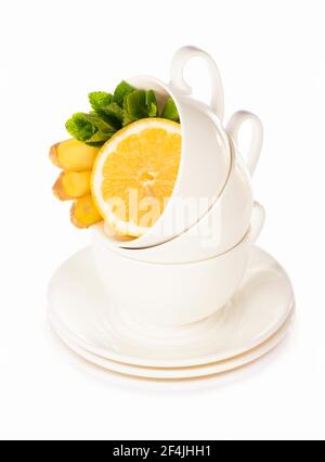 Layout creativo fatto di tazza di tè alla menta, limone, zenzero su sfondo bianco. Vista dall'alto. Foto Stock