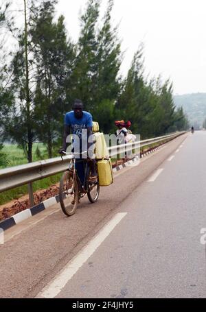 Un uomo ruandese che spinge la sua bicicletta caricata nella rurale Ruanda. Foto Stock