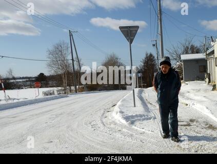 Un uomo giapponese anziano che cammina su una strada innevata in una piccola città nell'est di Hokkaido, Giappone. Foto Stock