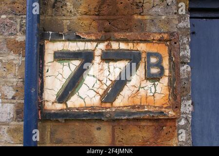 Vecchio segno di intemperie che mostra il numero 77 o settantasette B Foto Stock