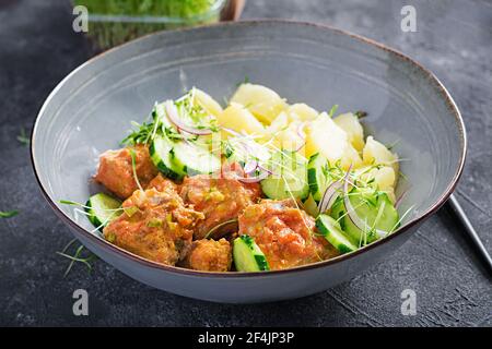Filetto di pesce al vapore con salsa di pomodori, patate bollite e insalata di cetrioli freschi. Pasto dietetico. Cibo Lenten. Foto Stock