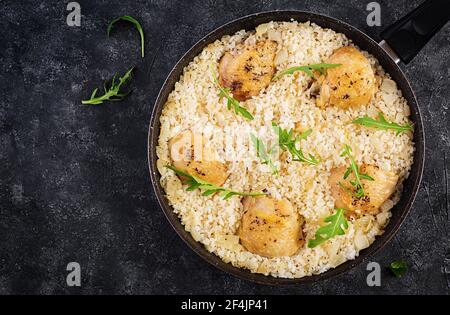 Riso con cosce di pollo, pilaf in padella su fondo scuro. Vista dall'alto, sopra, spazio di copia Foto Stock
