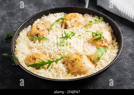 Riso con cosce di pollo, pilaf in padella su fondo scuro. Foto Stock