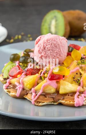 Cialda cuore con kiwi e ananas con caramella gommosa e gelato su di esso. Foto Stock