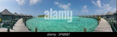 Panorama di Walkway in legno con Bungalows Overwater e Laccadive Sea nelle Maldive. Vista panoramica del Maldivian Resort con Ville sull'acqua. Foto Stock