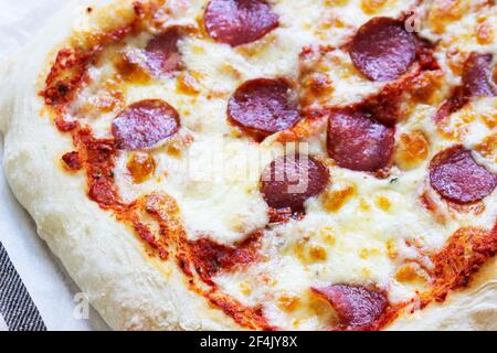Pizza fatta in casa con salsa di pomodoro, erbe, salsiccia e formaggio su un tavolo di legno. Foto Stock