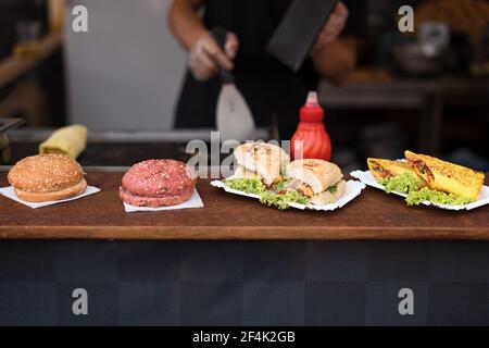 Chef che prepara hamburger di manzo all'aperto su una strada internazionale con cucina a vista evento del festival del cibo Foto Stock