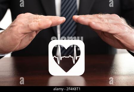 Simbolo heartbeat protetto dalle mani - concetto di assicurazione sanitaria Foto Stock