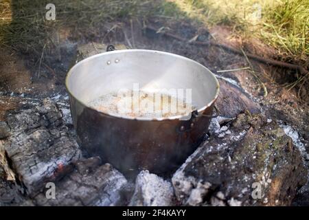 una pentola che cucina cibo all'aperto sul fuoco Foto Stock