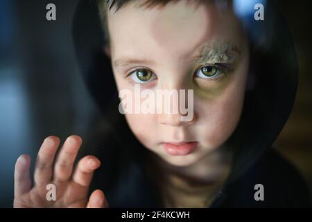 Povero ragazzo triste con sopracciglia tagliata in piedi in casa, concetto di povertà. Foto Stock