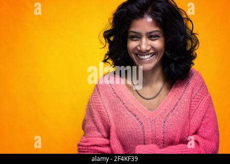 Bella Sri Lanka ragazza posa in piedi con giallo luminoso sfondo- La giovane donna sorride Foto Stock