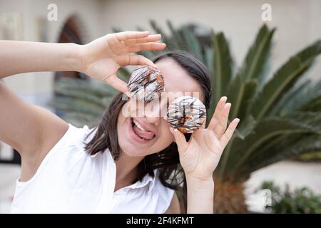 Ragazza divertente in posa con le ciambelle in estate all'aperto. Concetto di vacanza. Foto Stock