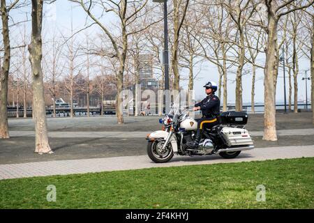 Jersey City, New Jersey, Stati Uniti. Poliziotto maschile che cavalca la sua moto Harley Davidson attraverso il parco Hudson Rover Shoreline. Foto Stock