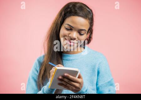 Donna africana che prende appunti nel pianificatore, donna matura che tiene la penna. Scrive i programmi futuri e l'elenco di cose da fare in taccuino per la settimana o il mese. Mantenere personale Foto Stock