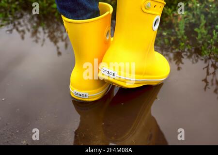 Tambov, Federazione Russa - 08 agosto 2019 Donna in giallo Cros stivali nel puddle. Primo piano Foto Stock