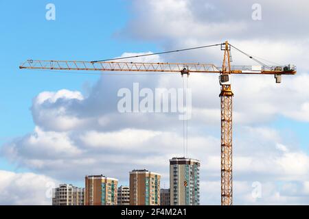 Costruzione di gru e edifici residenziali su cielo blu e sfondo bianco nuvole. Costruzione di alloggi in città Foto Stock