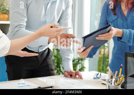 Immagine ritagliata di una donna d'affari che mostra il rapporto sul tablet digitale a. colleghi in riunione Foto Stock