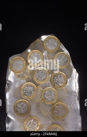 Fotografia di monete da £1 in un blocco di ghiaccio. Foto Stock