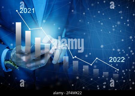 La mano dell'uomo d'affari tiene una visualizzazione del grafico di riserva in uno schermo visivo. Mostra segni di calo delle scorte nel 2021 con un indicatore grafico. Concetti di Foto Stock