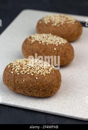 Un sano pane per cheto senza glutine, fatto di farina di mandorle e buccia di psyllium, cosparso di semi di sesamo. Cottura degli ingredienti in misurini. Dieta chetogenica Foto Stock