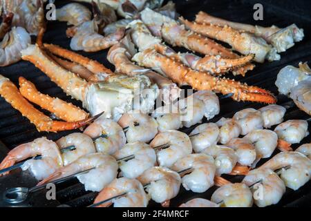 Una collezione di diversi tipi di pesce barbecue cucina su una griglia con gamberi su spiedini, e Alaskan re granchio Foto Stock