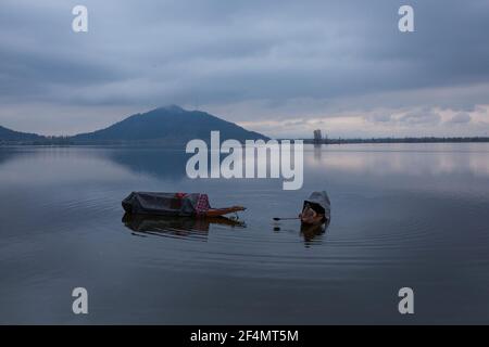 Srinagar. 22 marzo 2021. Un uomo rfila la sua barca sul lago dal alla periferia di Srinagar, la capitale estiva del Kashmir controllato dagli Indiani, il 22 marzo 2021, la Giornata Mondiale dell'acqua. Credit: Javed Dar/Xinhua/Alamy Live News Foto Stock