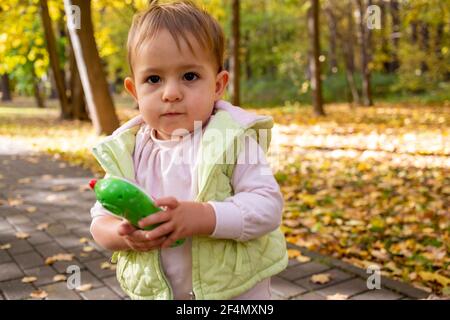 carino bambino serio che tiene un telefono giocattolo nel parco. Foto Stock