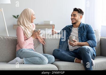 Giovane coppia musulmana che beve tè e parla a casa Foto Stock