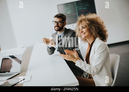 Gruppo multietnico di imprenditori che lavorano insieme e si applaudono dopo incontro riuscito in ufficio Foto Stock