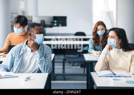 Studenti internazionali che indossano maschere mediche e parlano Foto Stock