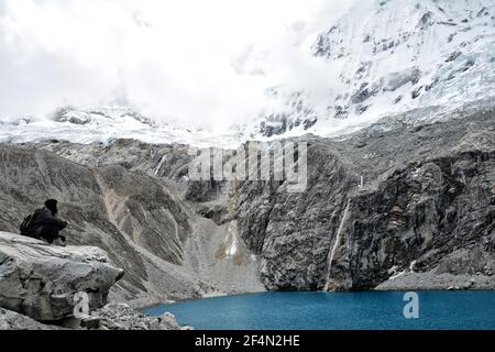 Ragazza seduta al lago di montagna Laguna 69 al Cordillera Blanca in Perù Foto Stock