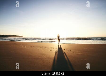 Silhouette di sola persona sulla spiaggia vuota. Vista posteriore dell'uomo durante la visione dell'alba. Costa sabbiosa dello Sri lanka. Foto Stock