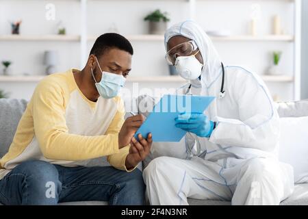 L'uomo afroamericano in maschera di faccia firma carte mediche Foto Stock