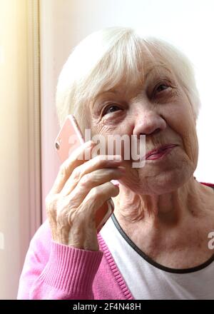 Ritratto di una donna anziana che tiene uno smartphone in mano. nonna di 85 anni che parla al telefono. Foto Stock