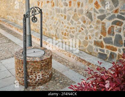 Bene per estrarre acqua sotterranea fatta di pietra e tradizionale stile con elementi decorativi Foto Stock