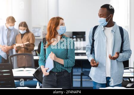 Studenti internazionali che indossano maschere mediche e parlano Foto Stock