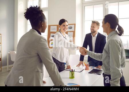 I giovani sorridenti si salutano reciprocamente prima di negoziare al ufficio aziendale Foto Stock