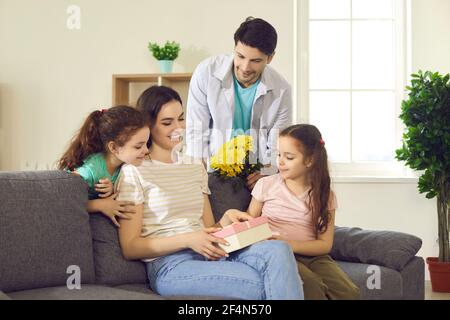 Felice giovane donna ottiene i regali dal suo marito amorevole e. Bambini nel giorno delle madri Foto Stock