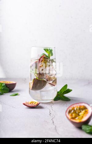 bevanda rinfrescante con frutto della passione. cocktail con frutta tropicale su sfondo chiaro. con foglie di menta verde. posizione verticale Foto Stock