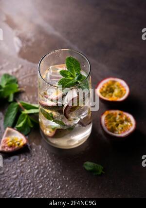 bevanda rinfrescante con frutto della passione. cocktail con frutta tropicale su sfondo scuro. con foglie di menta verde. posizione verticale Foto Stock