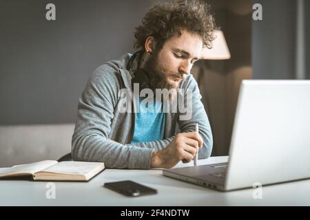 Lavoro stasera. Freelance lavora da casa. Un uomo stanco lavora su un computer portatile di notte. Foto Stock