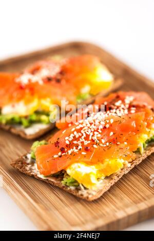 Salmone salato, uova strapazzate, avocado e pane tostato croccante di segale al formaggio Foto Stock