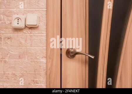 Parte dell'interno di un moderno soggiorno con una porta in ferro, presa e interruttore luce da vicino. Foto Stock