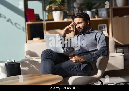 Dirigente indiano uomo d'affari che lavora su un computer portatile seduto sulla sedia in ufficio. Foto Stock