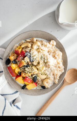 Porridge vegetariano di farinata d'avena con frutta e semi di canapa in una ciotola di argilla, vista dall'alto. Colazione sana, porridge di avena vegana senza glutine Foto Stock