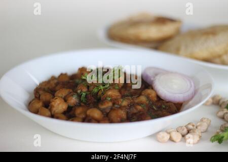 Salsa piccante di ceci con pane piatto indiano fritto. Localmente conosciuto come Chole puri. Scatto su sfondo bianco Foto Stock