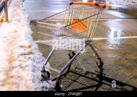 Un carrello abbandonato in piedi sulla strada vicino al supermercato in inverno. Foto Stock