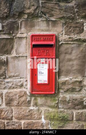 Casella postale Royal Mail rossa in vecchio secco storico Muro di pietra posizione rurale ER logo e tempi di raccolta - Editoriale Foto Stock